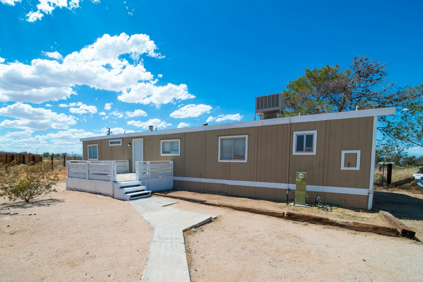 A light brown manufactured home with a white porch.